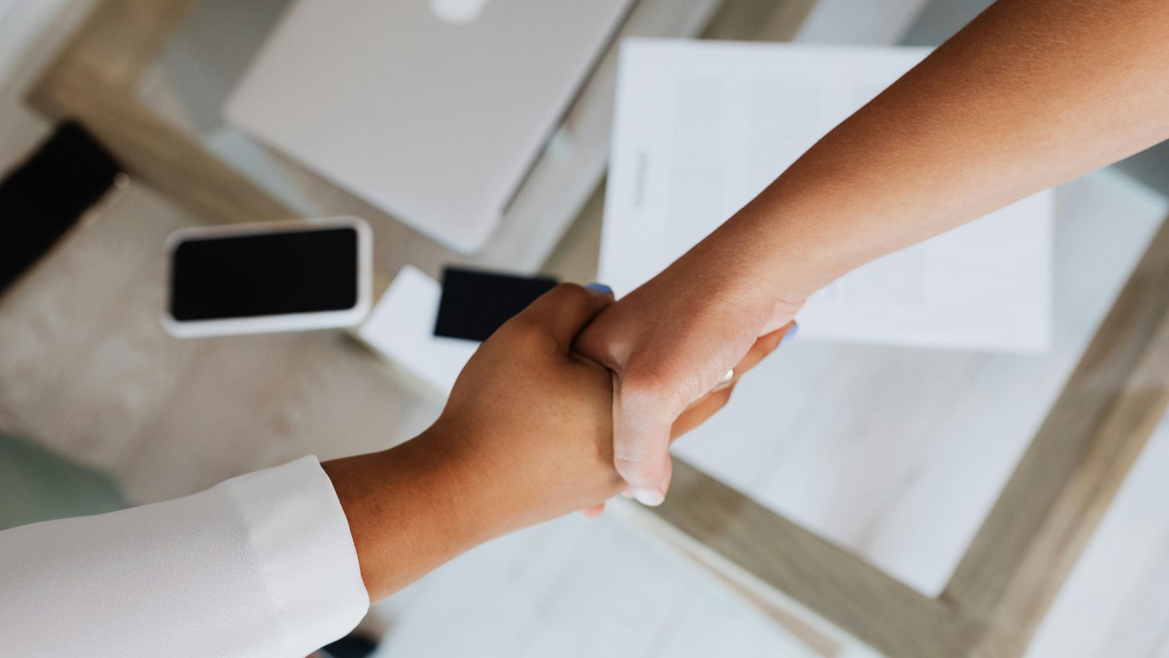 Overhead view of two people shaking hands at a desk